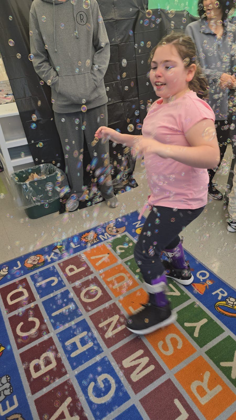 Child standing on an alphabet rug with bubbles around
