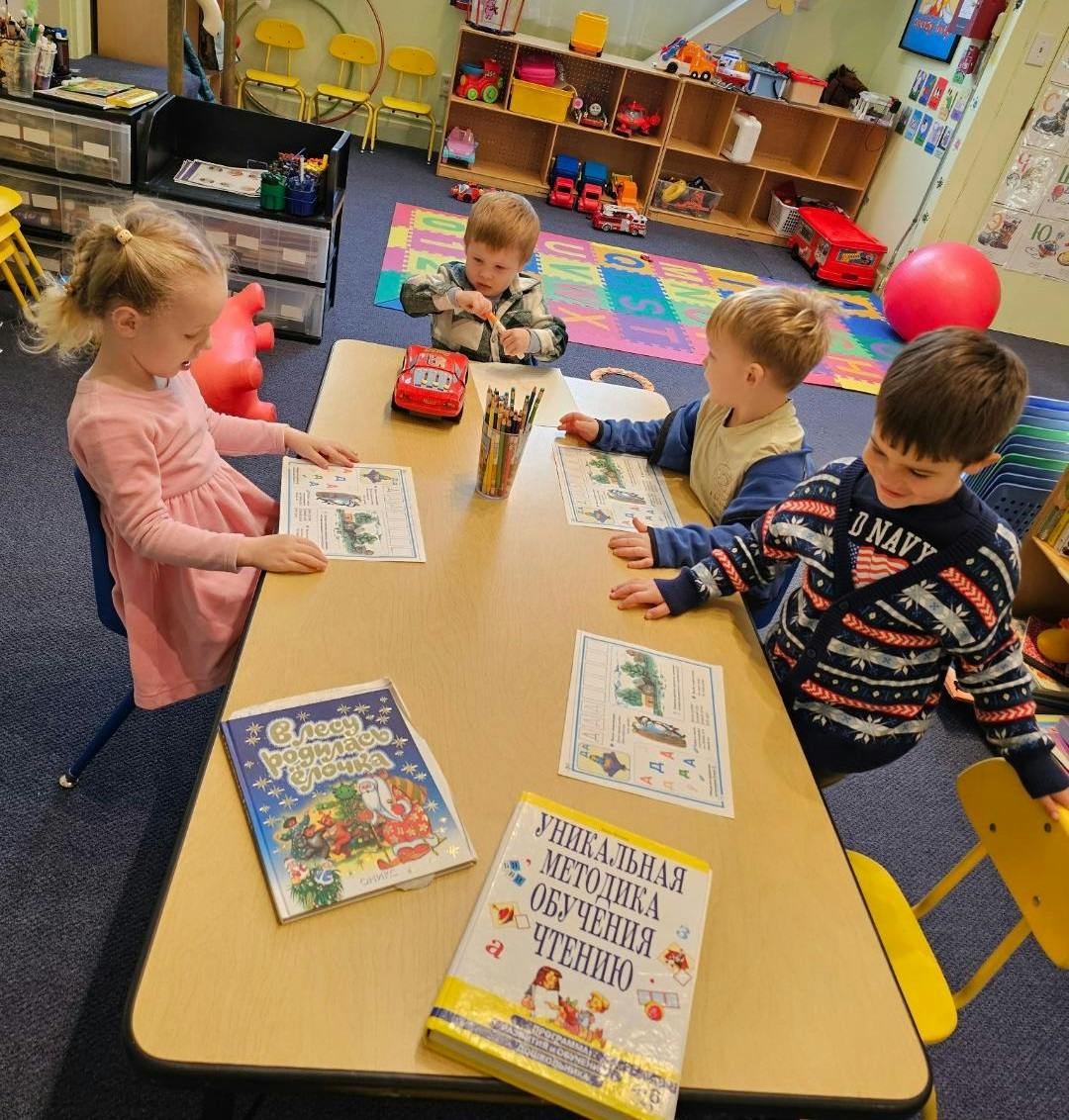 Four children sitting at a table with books and papers