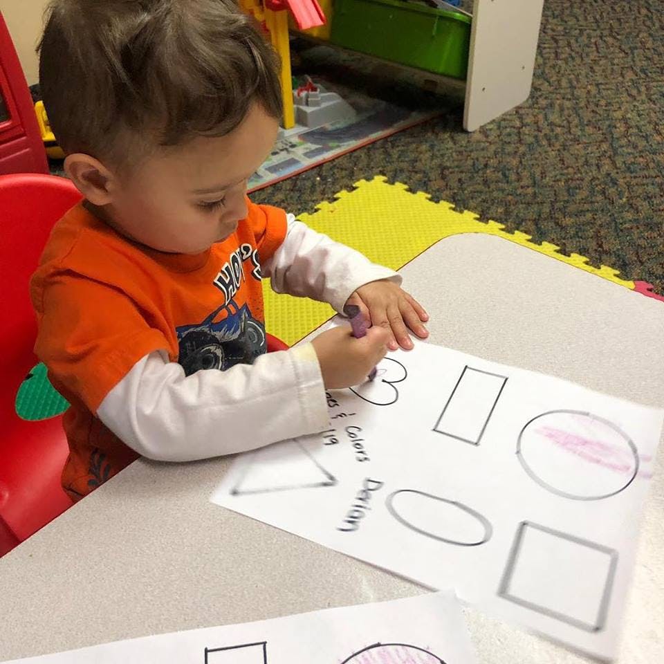 Child coloring shapes on a piece of paper