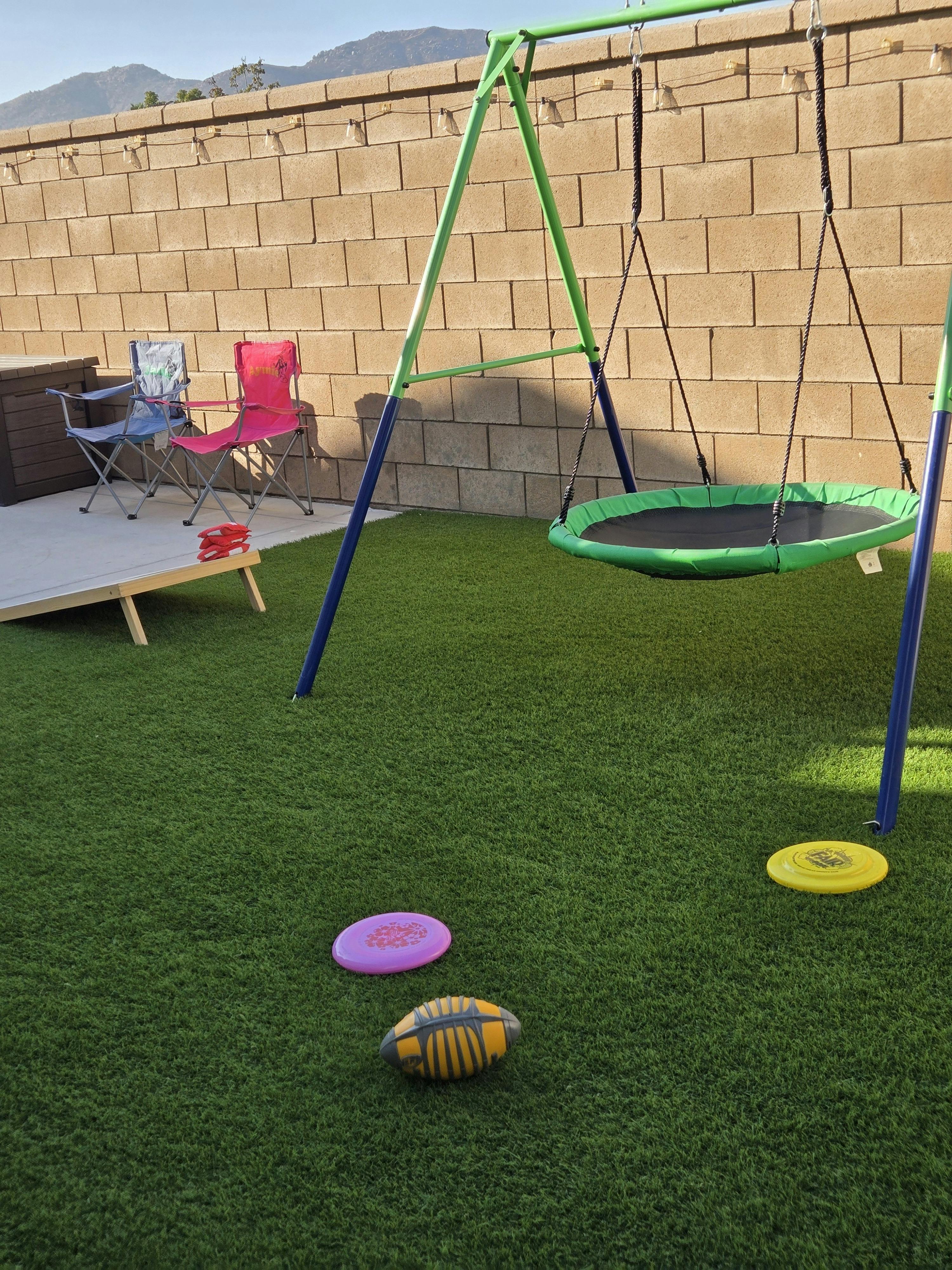 Backyard with a saucer swing, folding chairs, and scattered sports toys