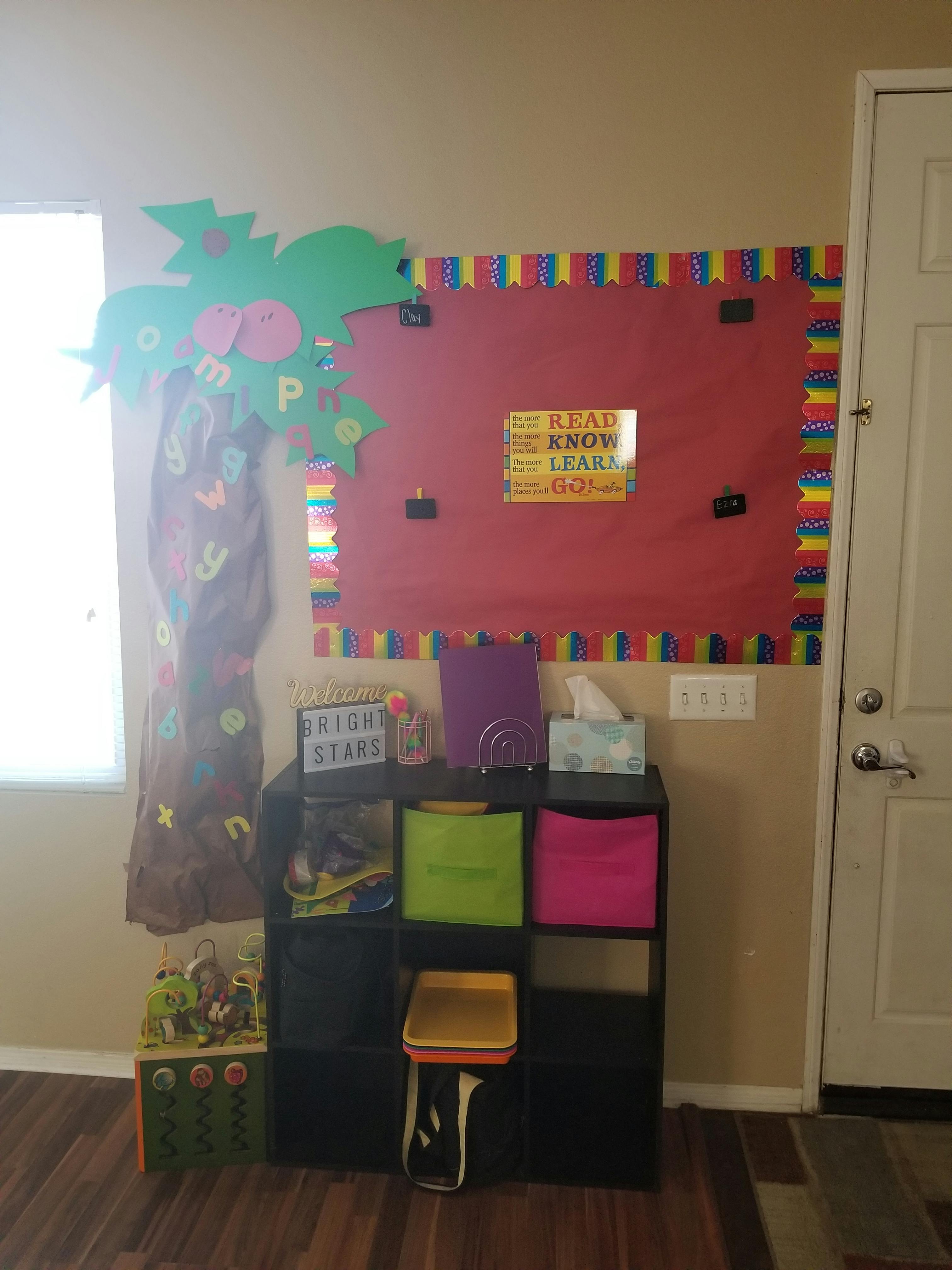 Bulletin board with colorful border and tree cutout next to storage shelves