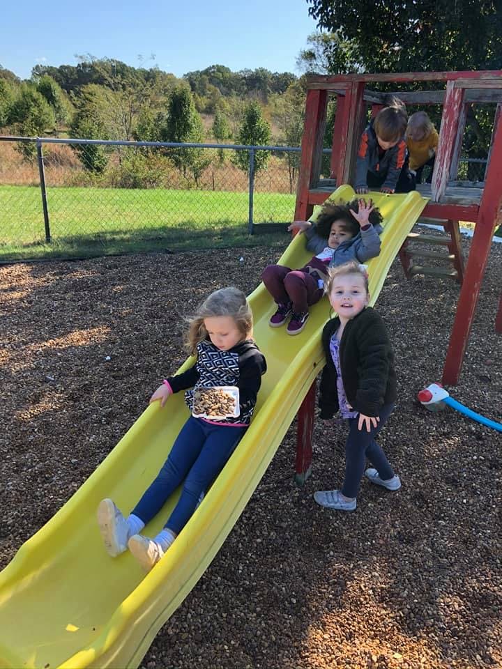 Children playing on a yellow slide on a playground