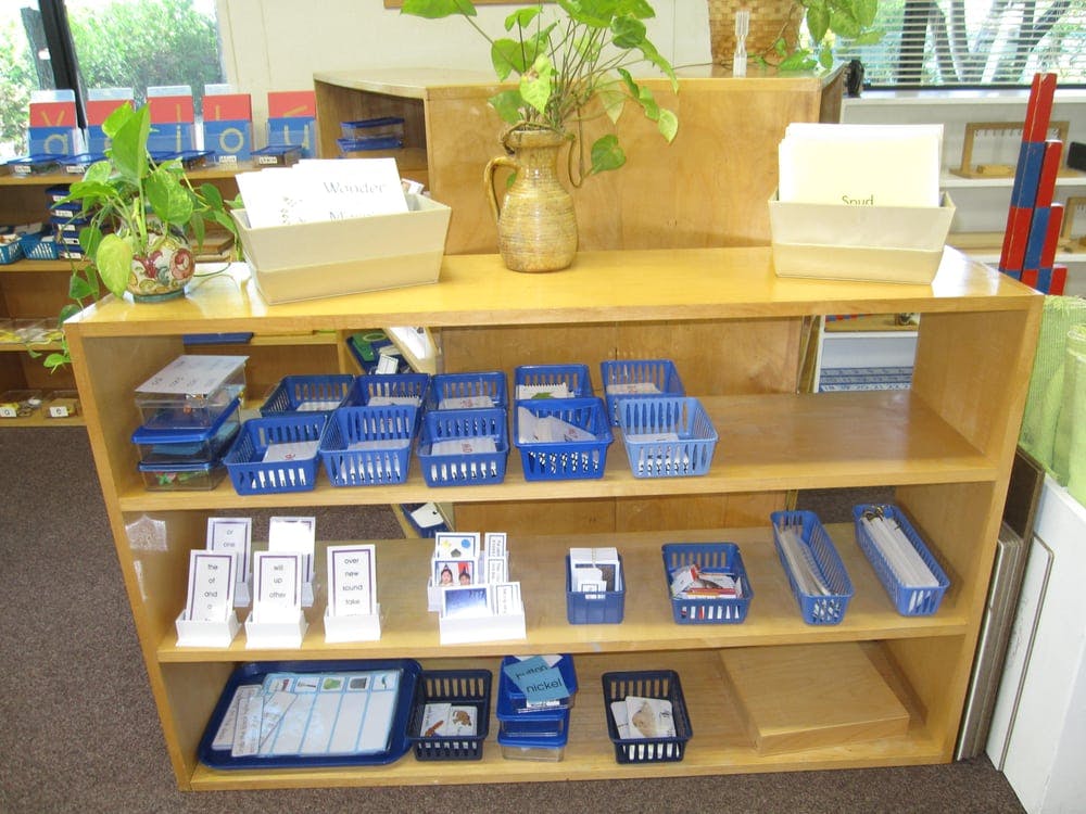 Shelves with various learning materials in blue baskets and trays