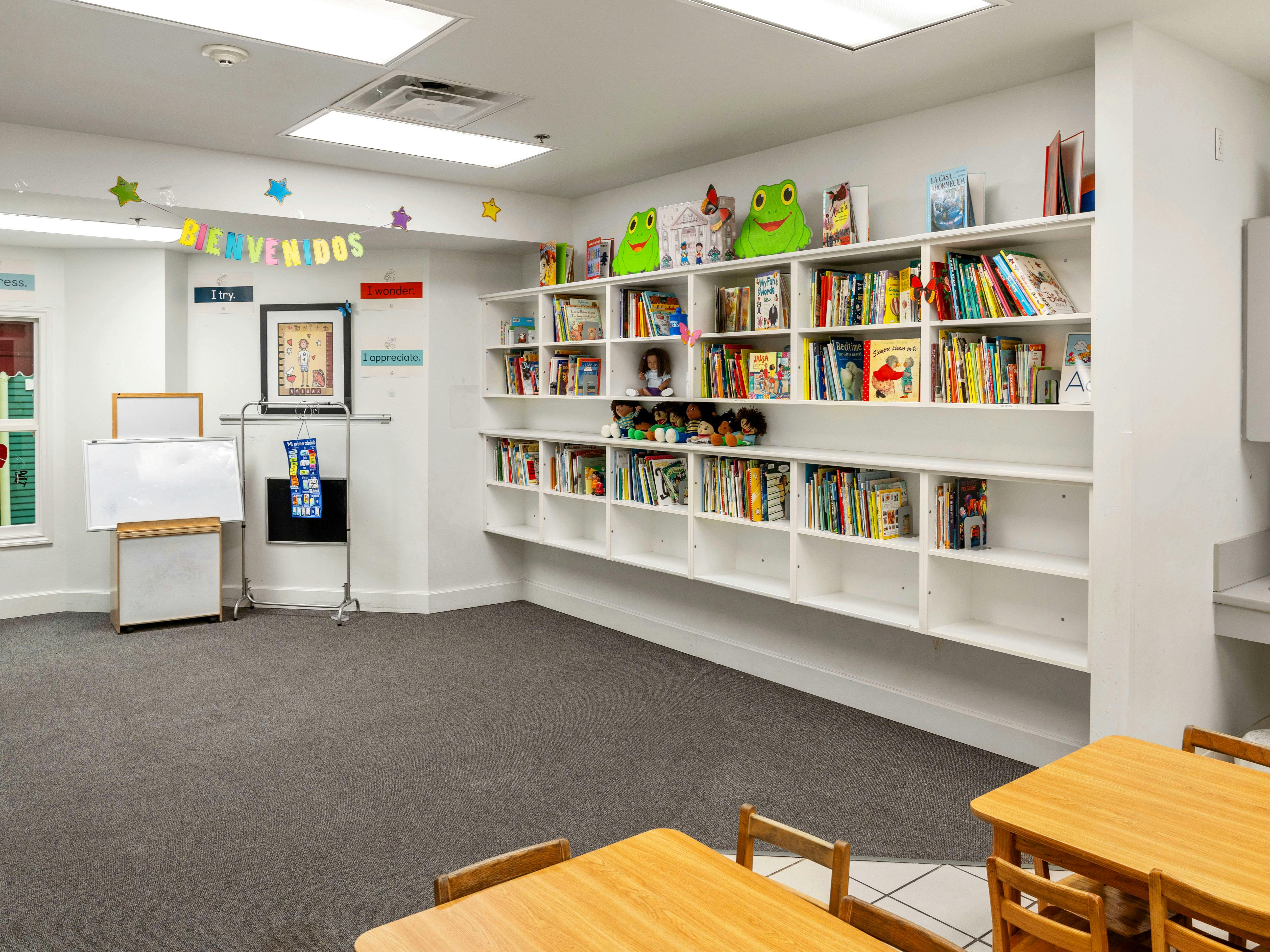 Children's classroom with book display, whiteboards, and a colorful "BIENVENIDOS" sign