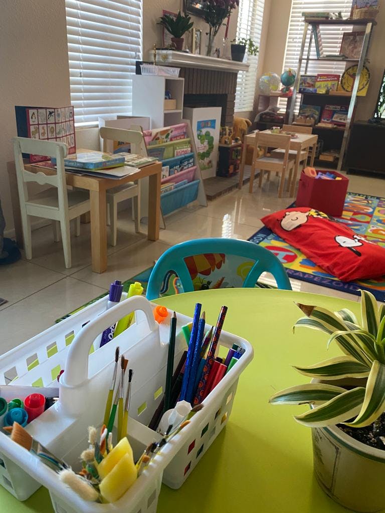 Art supplies in a white caddy on a green table in a classroom