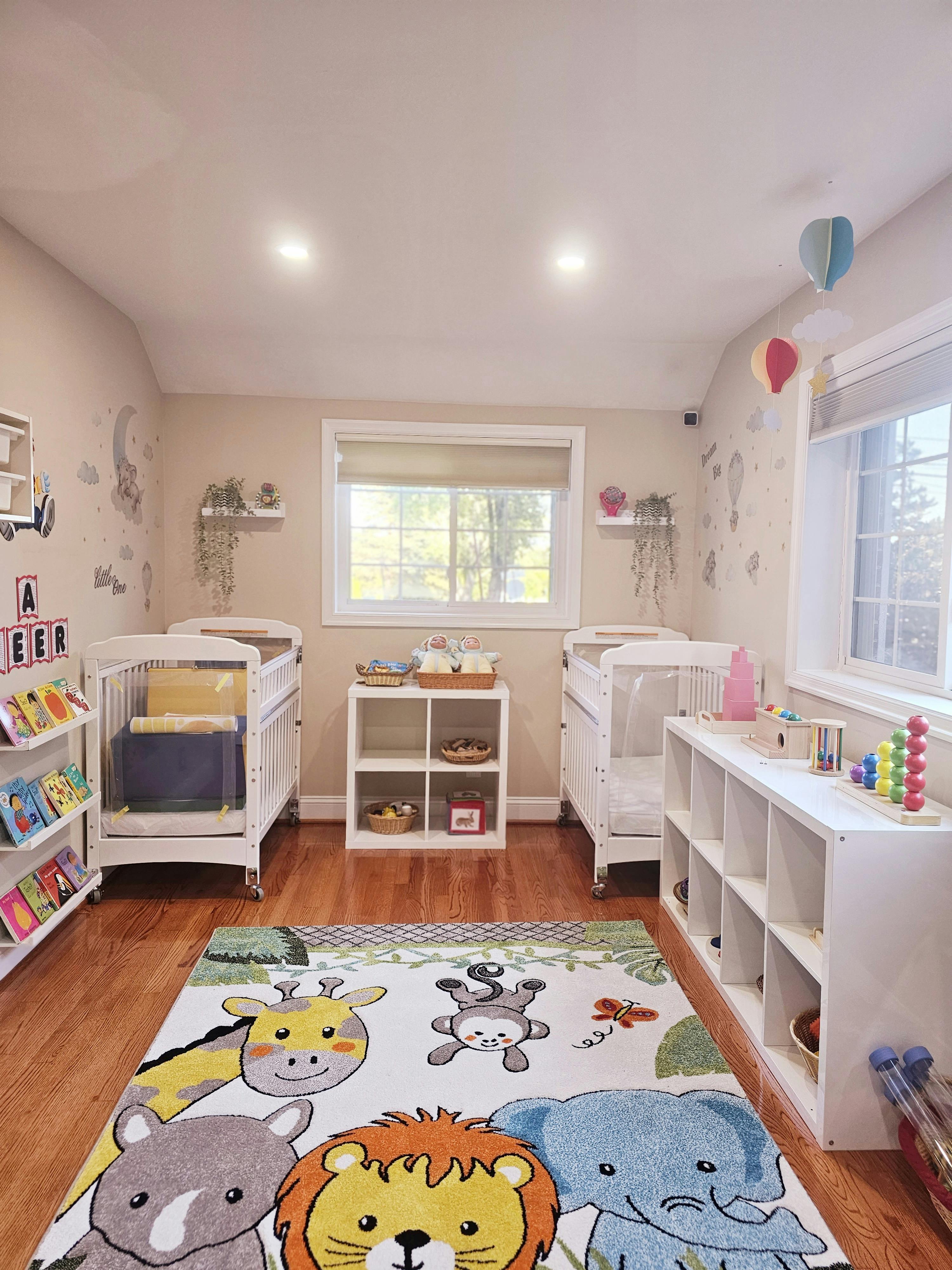 Nursery room with two cribs, shelves, and an animal-themed rug