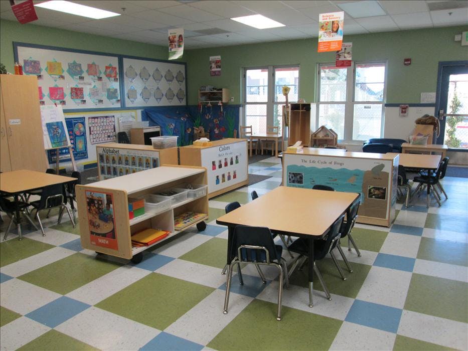 Empty preschool classroom with small tables and chairs
