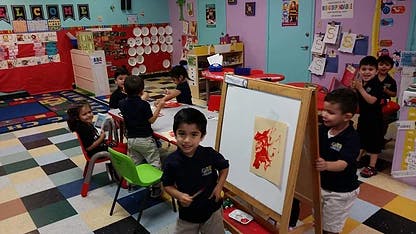 Children in a classroom with one child standing by an easel