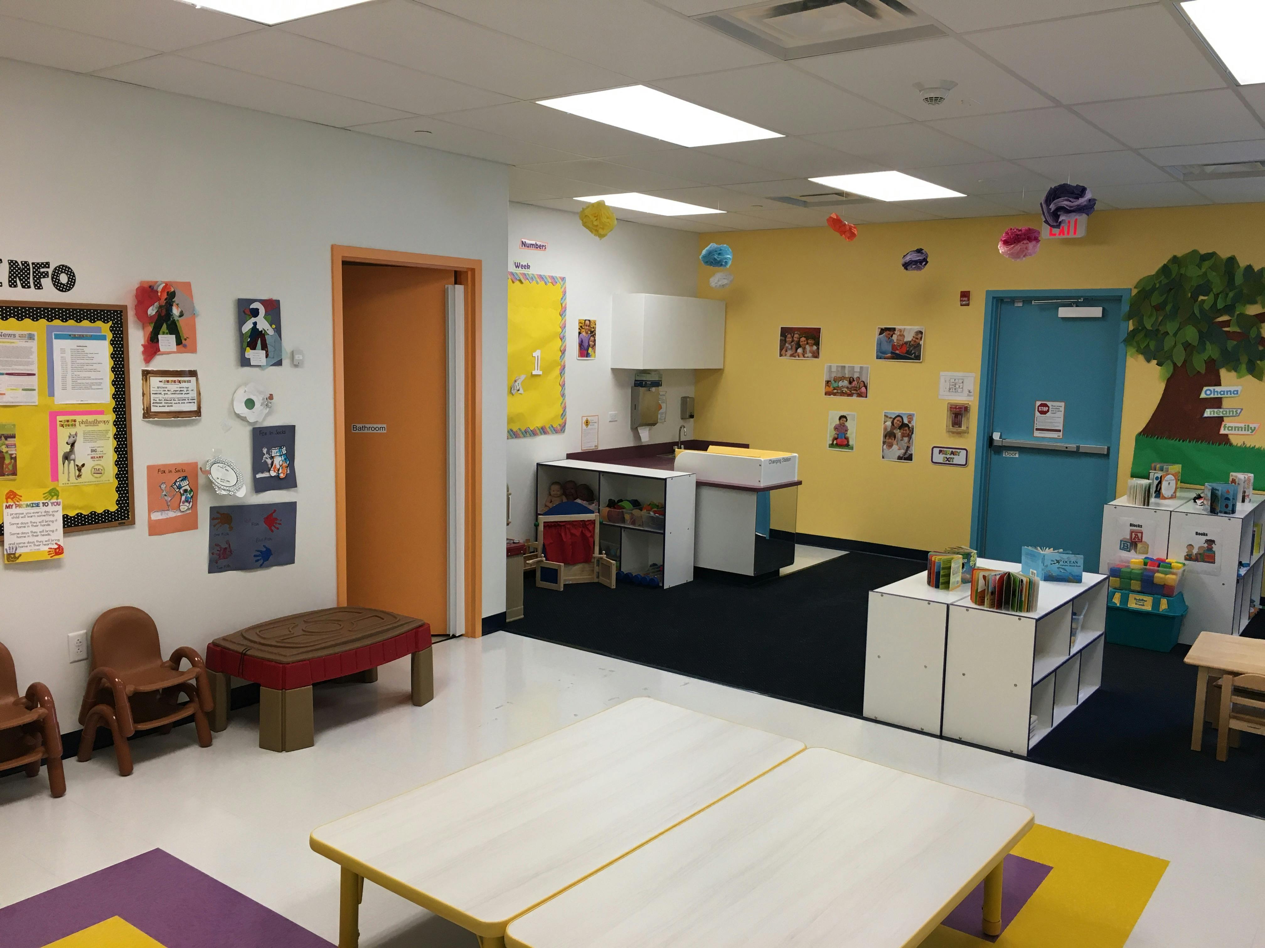 Classroom with small tables and chairs, bulletin board, and colorful wall decorations