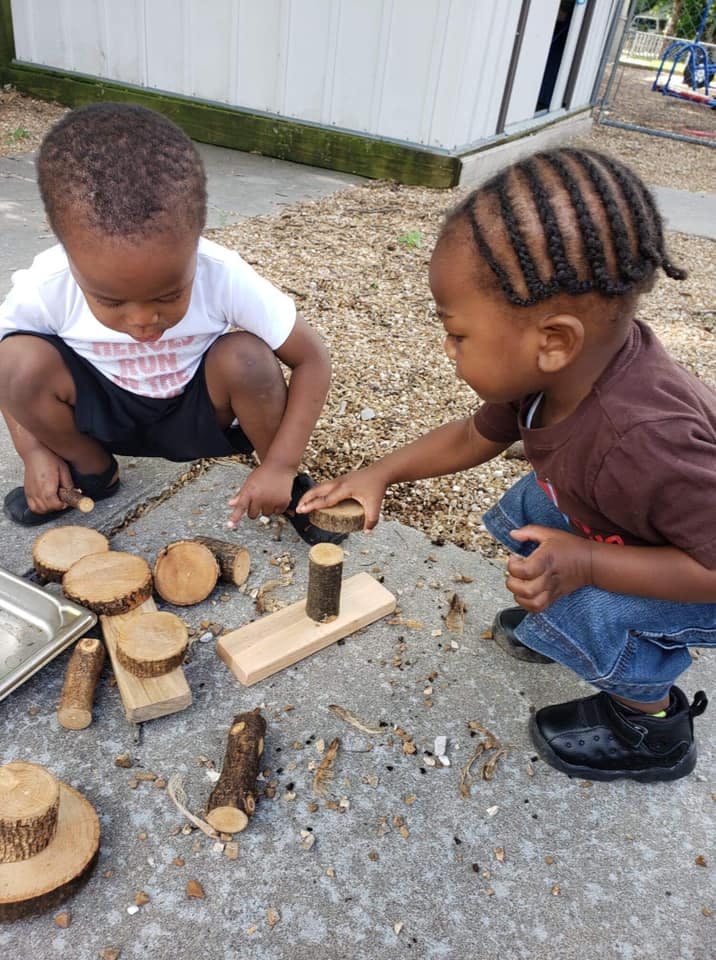Two children playing with wood blocks outdoors