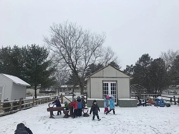 Children playing in the snow outside a building