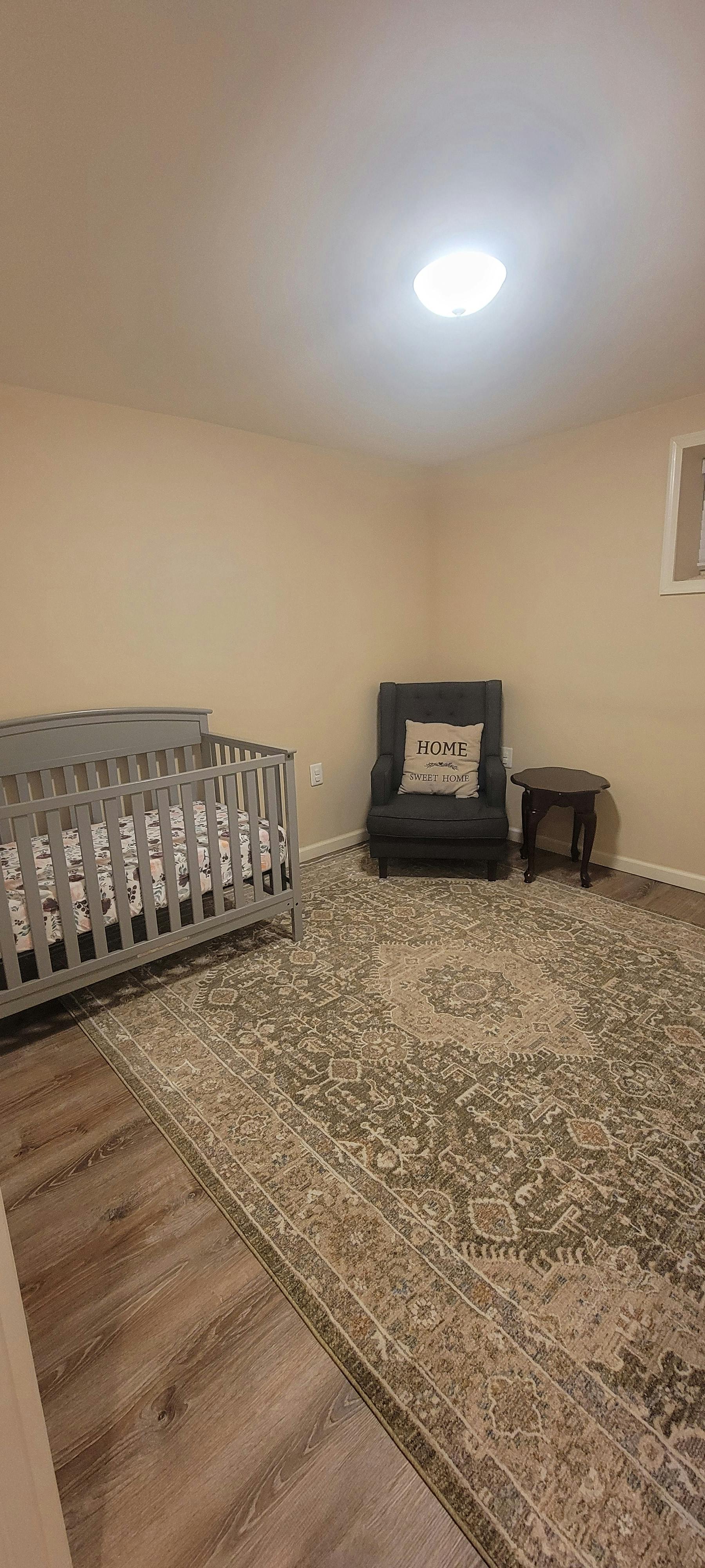 Crib and armchair with Home Sweet Home pillow in a nursery