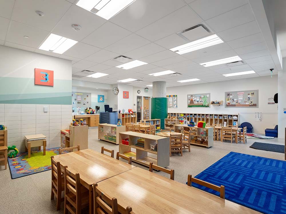 Spacious daycare classroom with tables, chairs, and play areas
