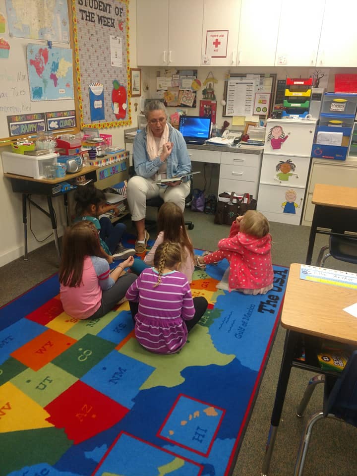 Adult reading to children sitting on a colorful rug in a classroom