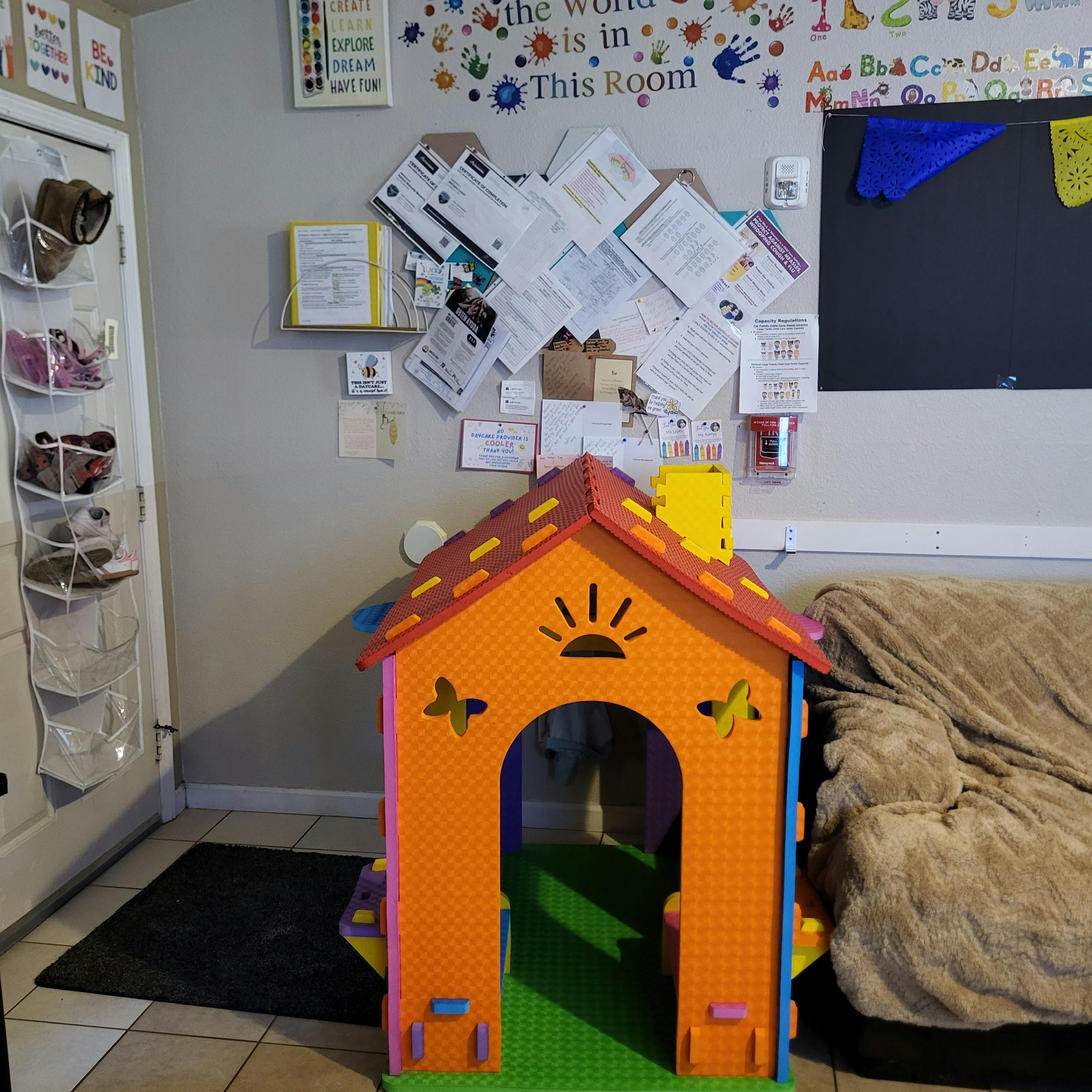 Colorful foam playhouse in a room with papers on the wall and shoes in an organizer