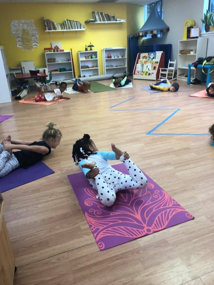 Children doing yoga poses on mats in a classroom