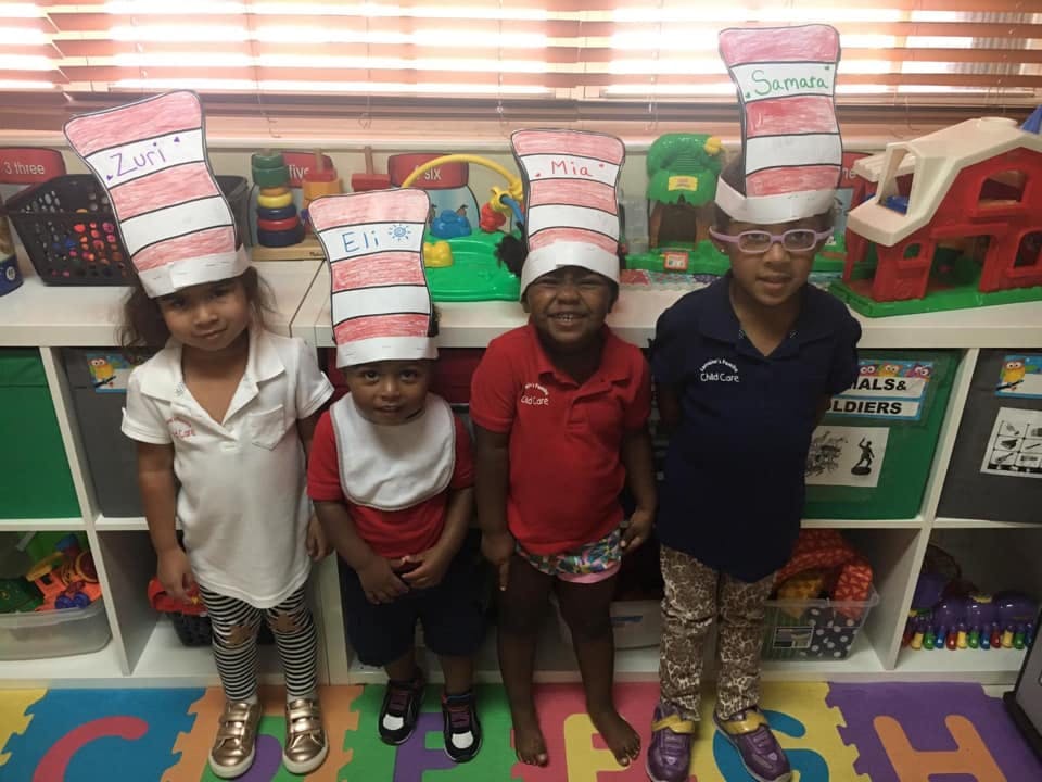 Four children wearing striped paper hats