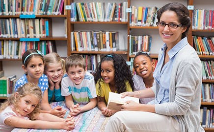 Adult reading to a group of children in a library