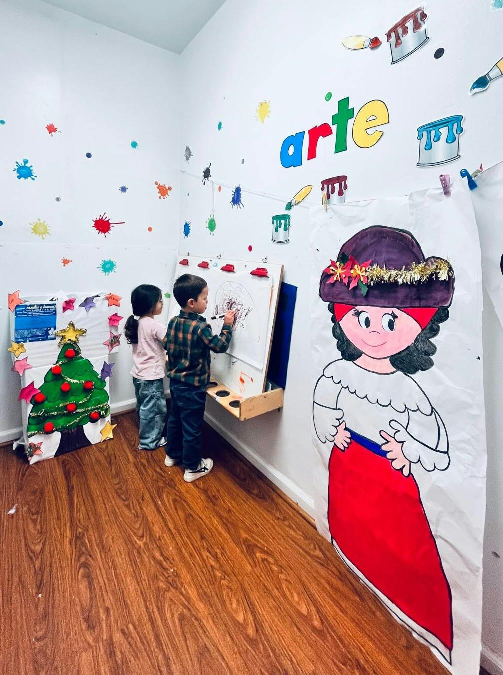 Two children drawing on an easel in a room decorated with art supplies