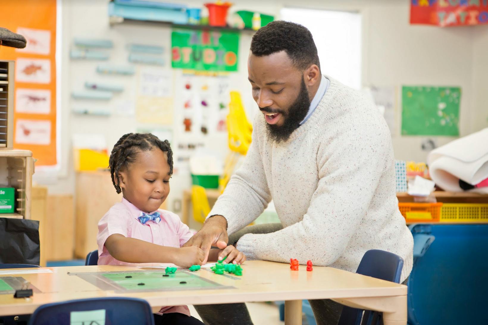 Person and child playing a board game in a classroom