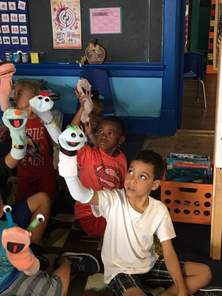 Children playing with puppets in a classroom