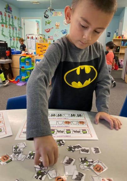 Child in a Batman shirt doing an activity with small cutouts