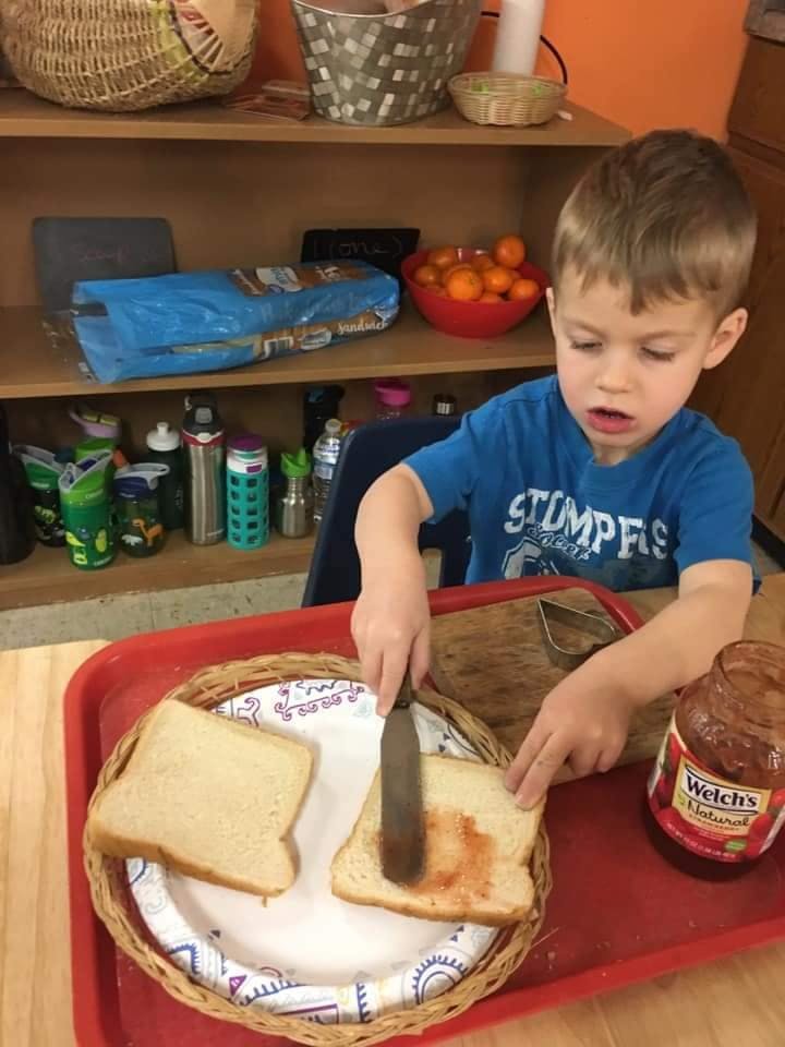 Child spreading jam on bread
