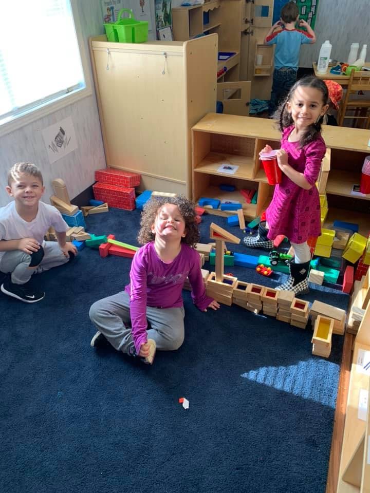 Three children playing with blocks on a blue carpet