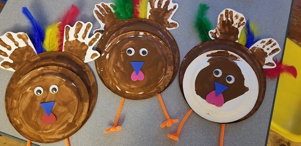 Three paper plate turkey crafts with handprint feathers