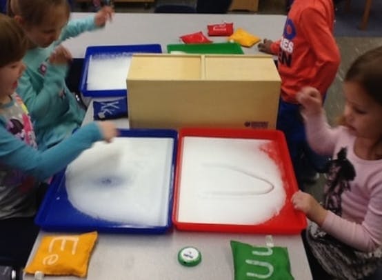 Children playing with sensory trays filled with white material