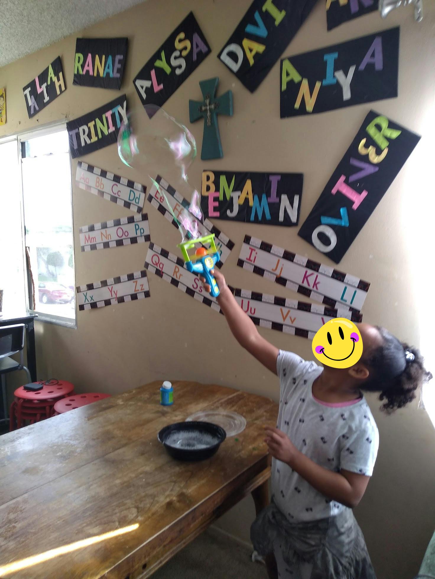 Child making bubbles in a classroom