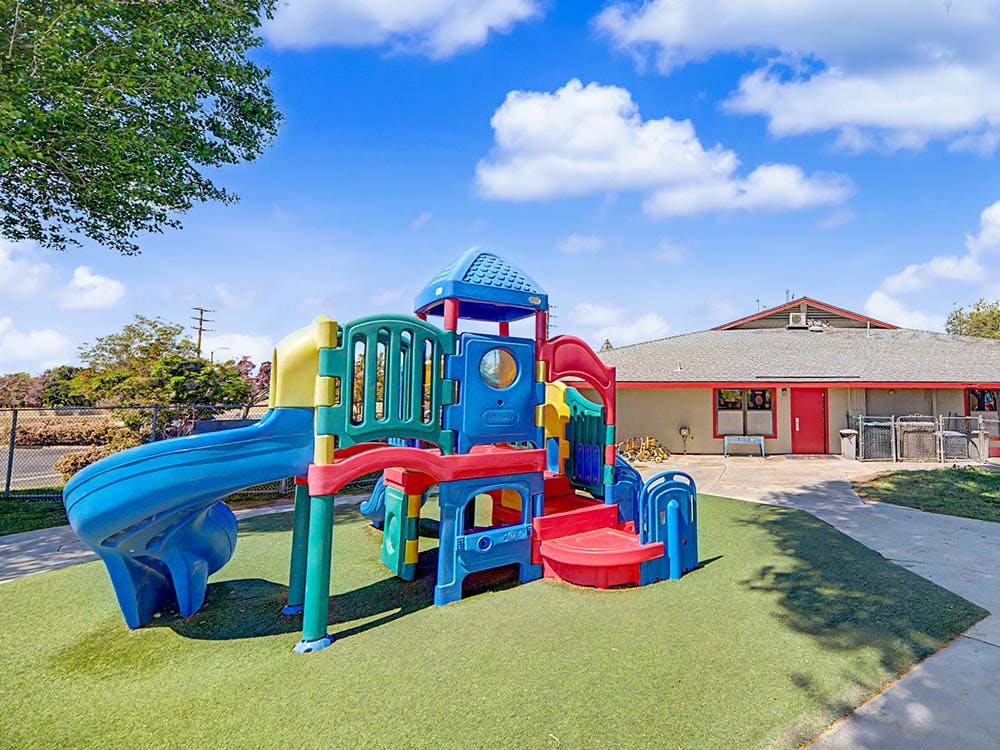 Colorful plastic playground slide and climbing structure on artificial turf