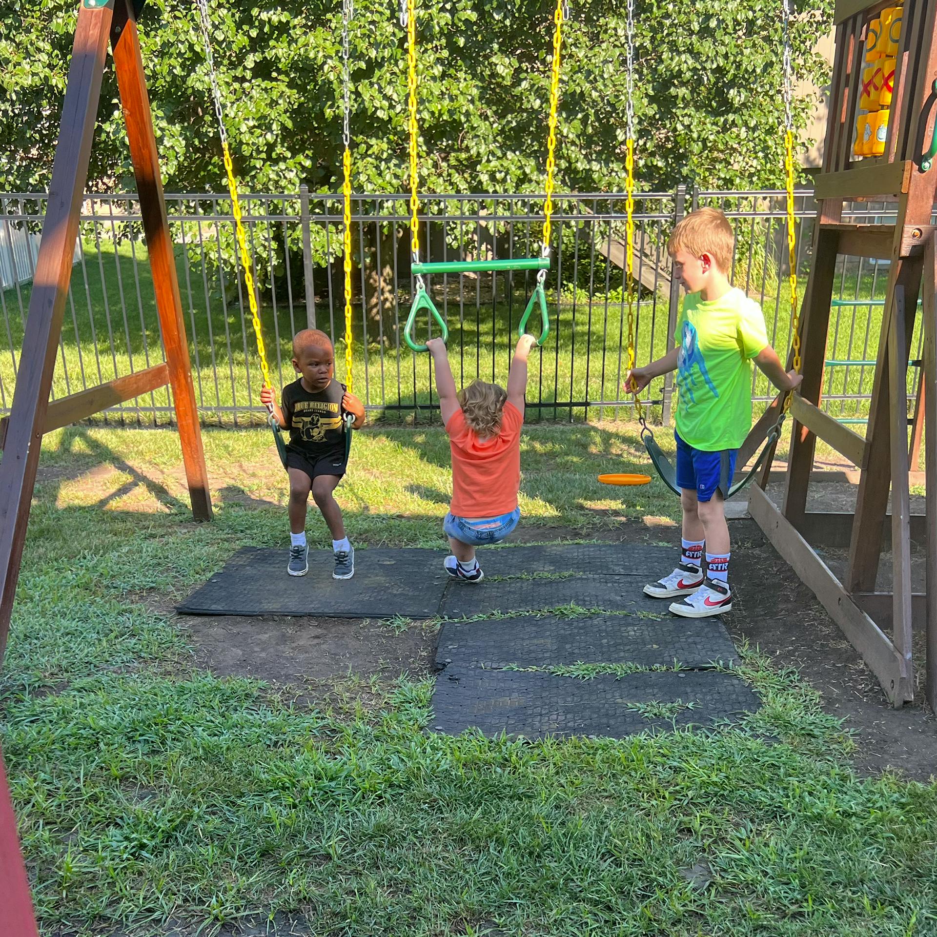 Three children playing on a swing set