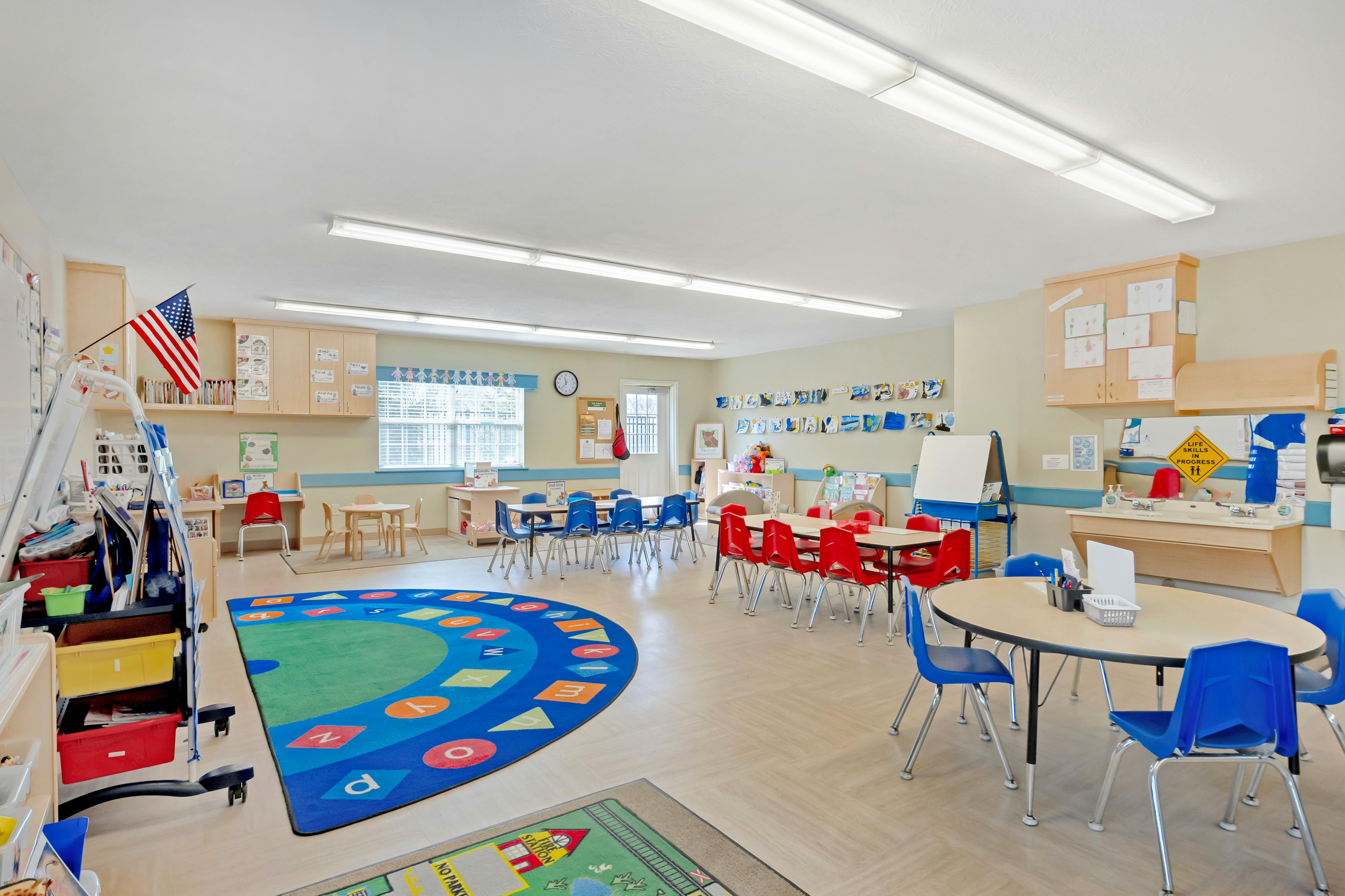 A classroom with small tables and chairs, and a sink