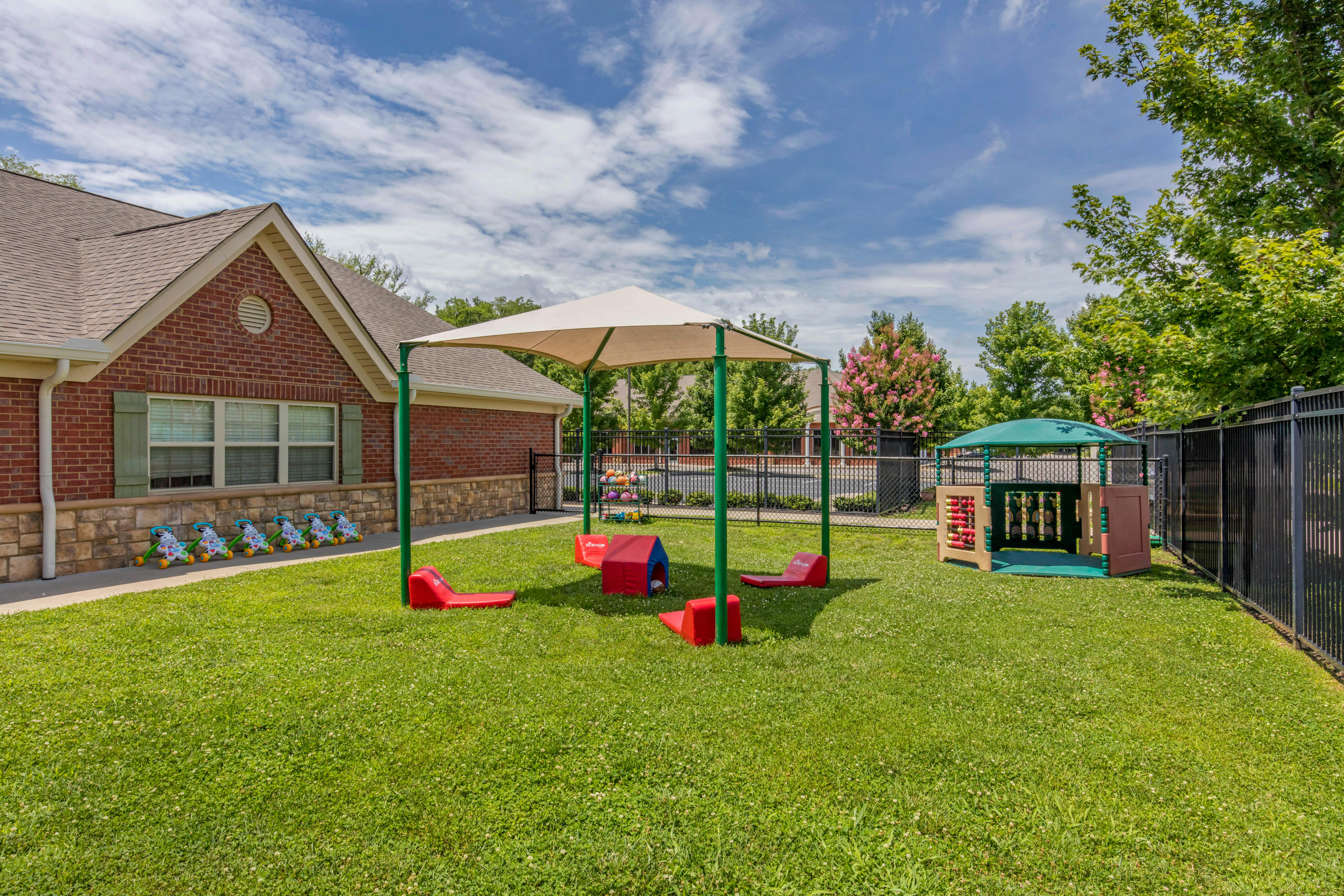 An outdoor playground with a brick building in the background, featuring various play equipment