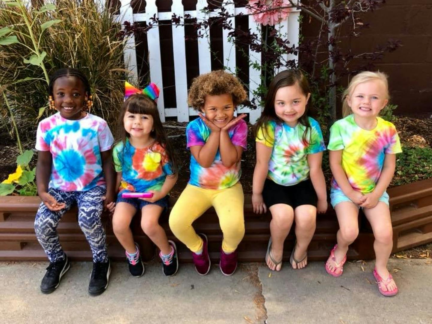 Five children in tie-dye shirts sitting together