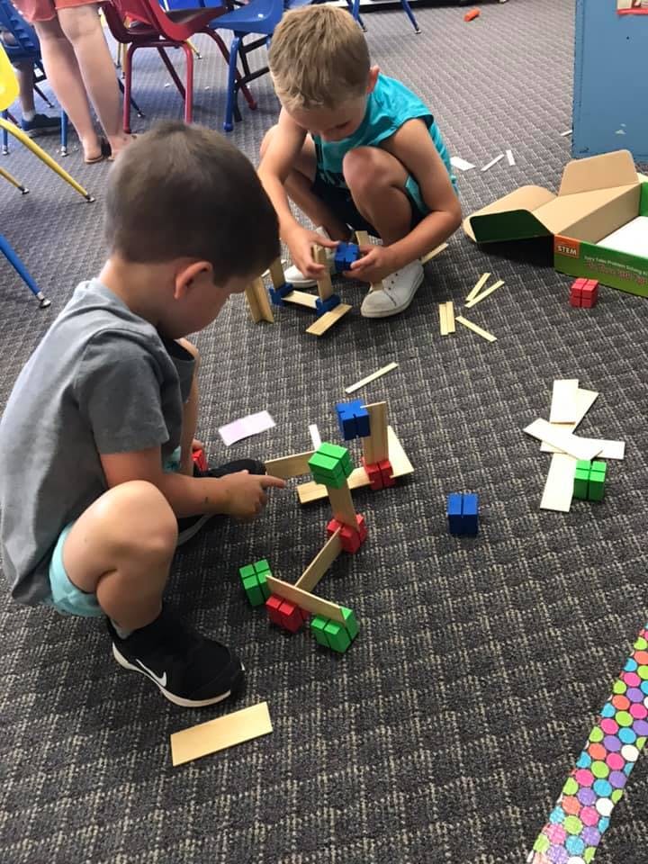 Two children playing with building blocks on a carpeted carpet