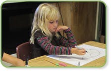 Child drawing on paper at a desk