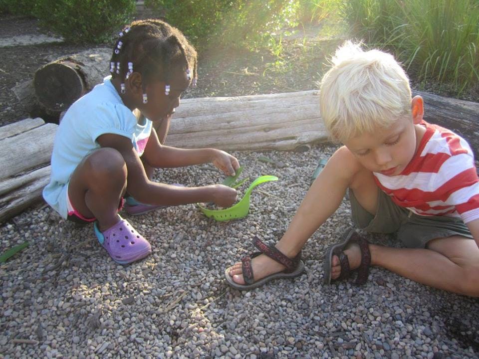 Two children playing on the ground with a green object