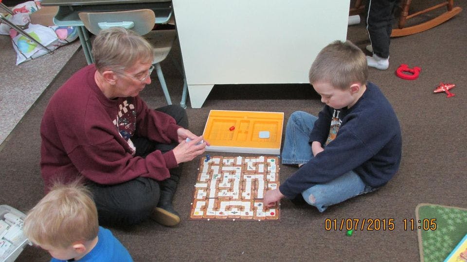 Person and child playing a board game on the floor