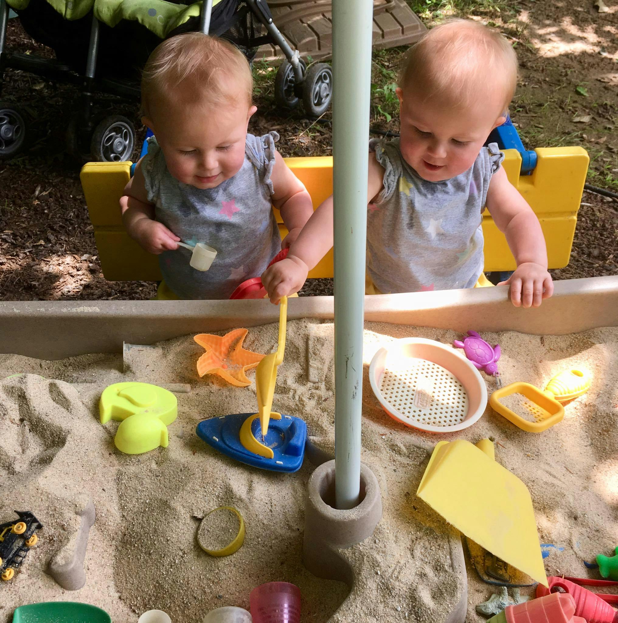 Two children playing in a sandbox with toys