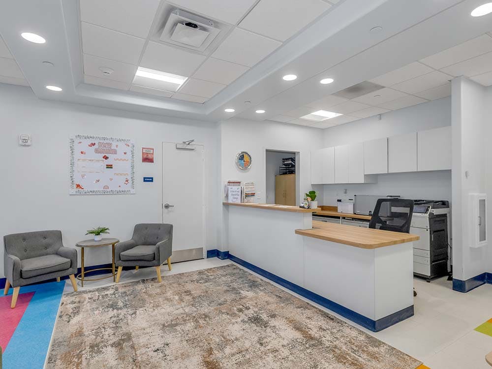 Reception desk with two chairs and a small table in a brightly lit office