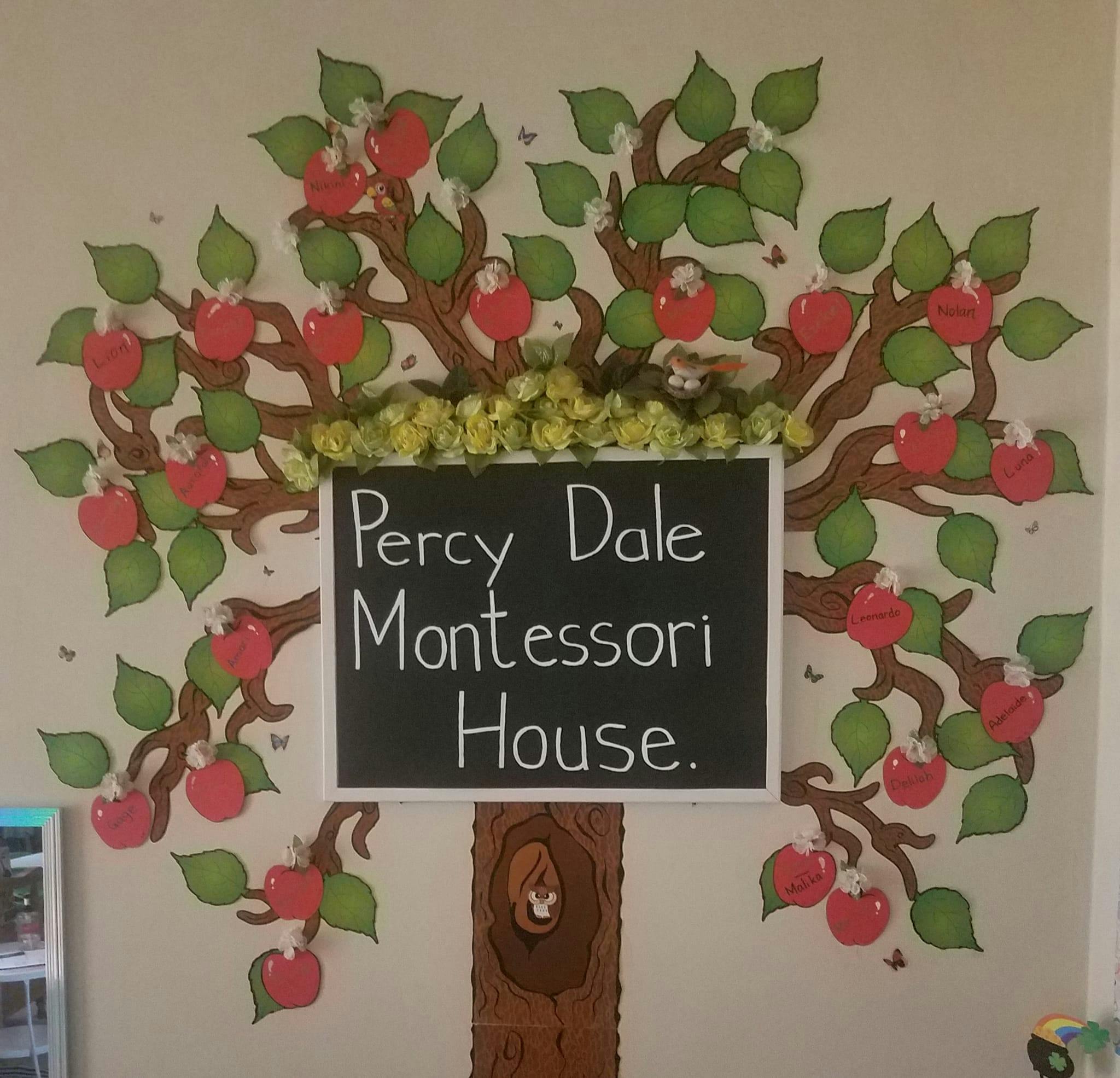 Chalkboard sign with "Percy Dale Montessori House" surrounded by an apple tree