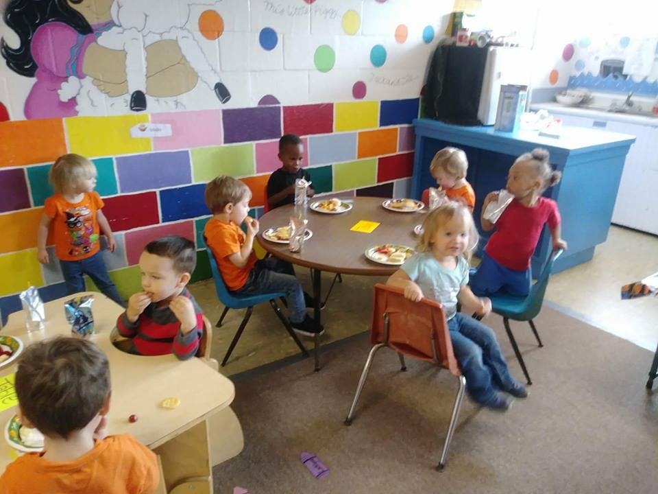 Children eating at tables in a classroom