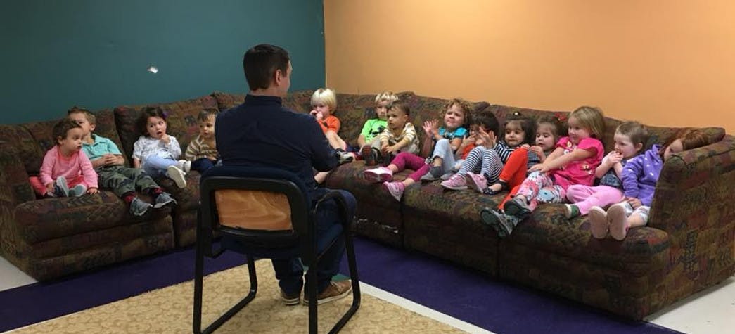Person sitting in a chair facing children on a couch