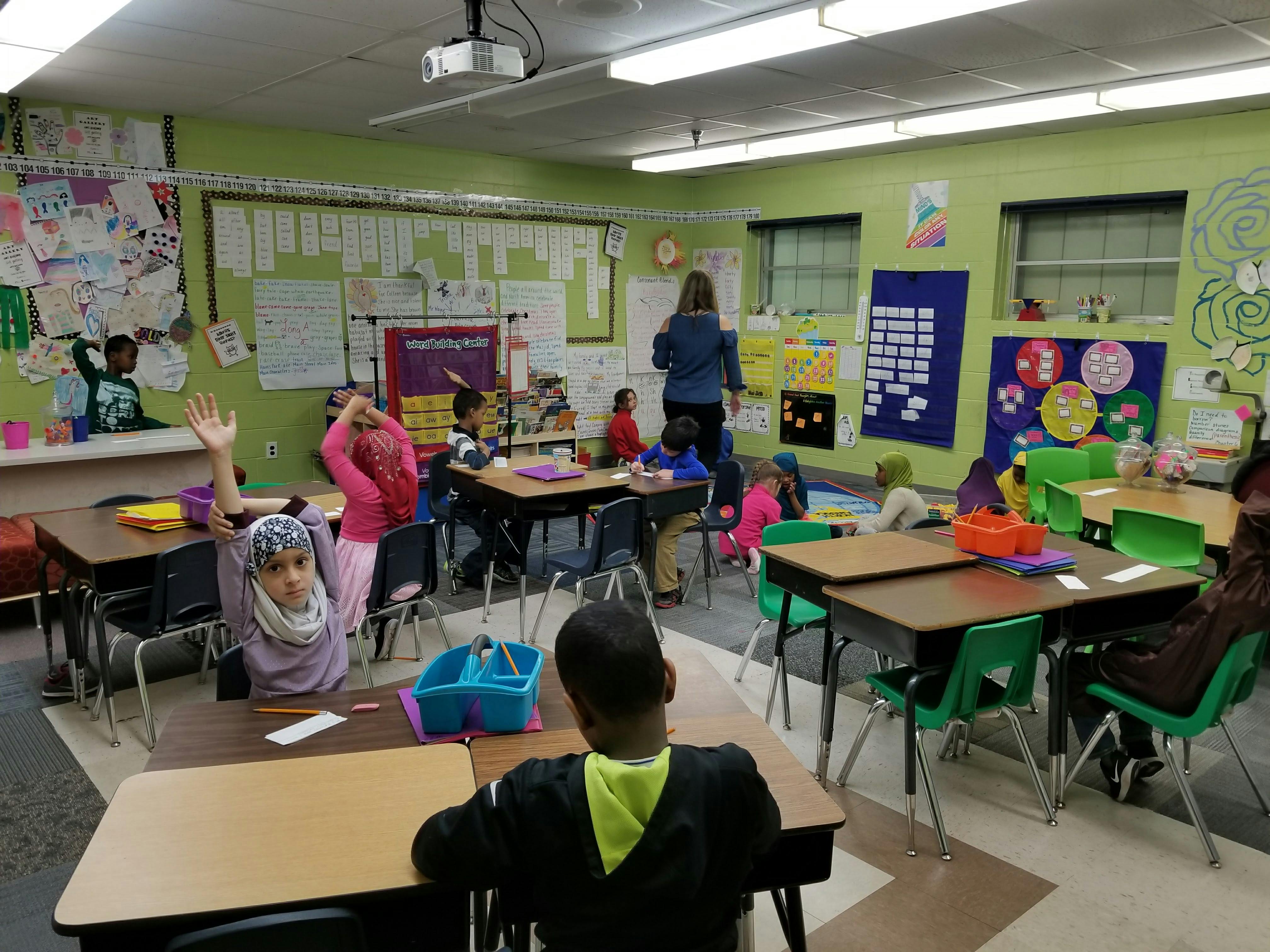 Children in a classroom, one child raising a hand