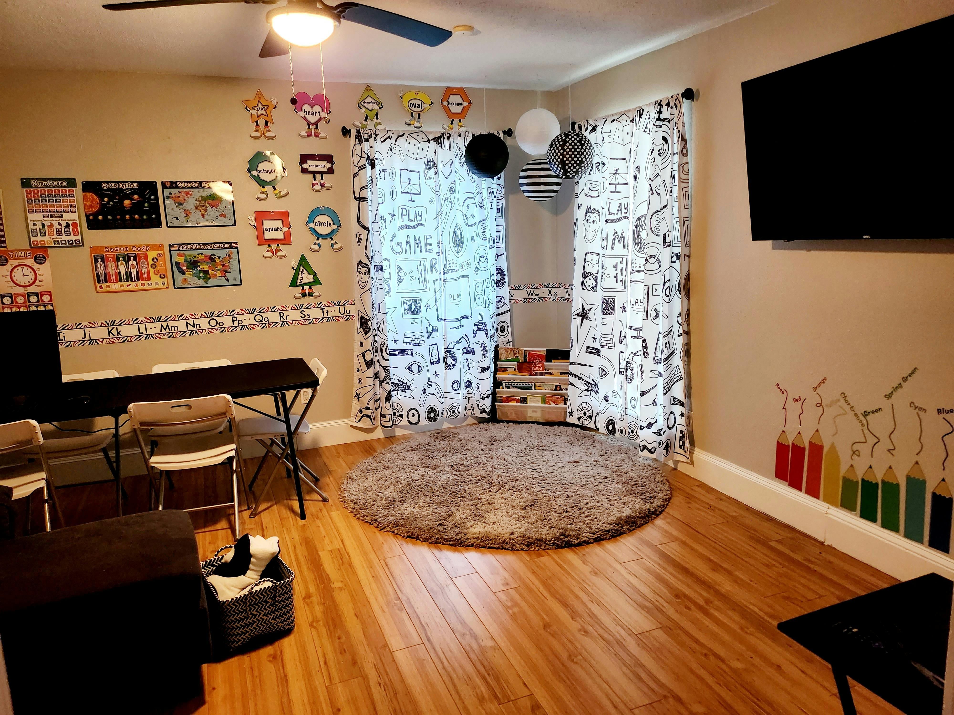 Room with a desk, chairs, and a round rug on a wooden floor