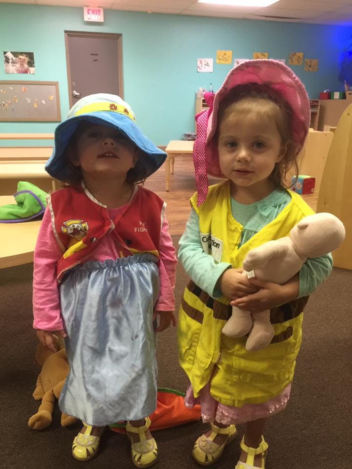 Two children in costumes, one holding a doll