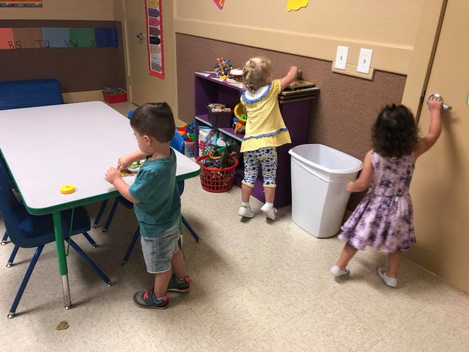 Three children playing in a classroom