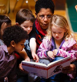 Adult and three children looking at a book